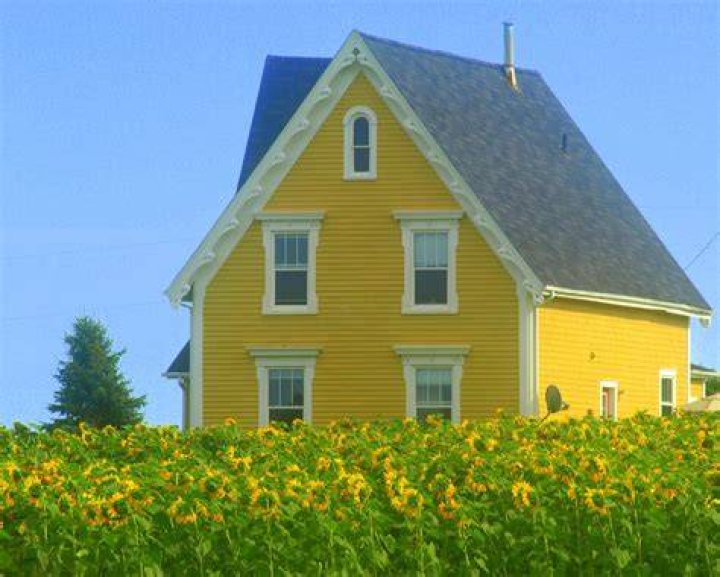a large yellow house with a black and white sign in front of it on a